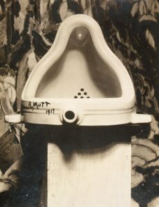 Marcel Duchamp Fountain, 1917, photograph by Alfred Stieglitz at 291 art gallery following the 1917 Society of Independent Artists exhibit, with entry tag visible. The backdrop is The Warriors by Marsden Hartley.