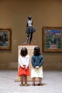 girls looking to Degas little dancer in a museum